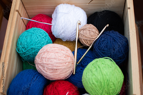 box resting on the ground full of colored yarns and with knitting needles, crochet