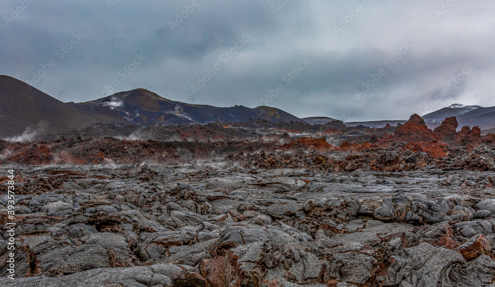 Panoramic view of the lava field. White steam comes from the ground