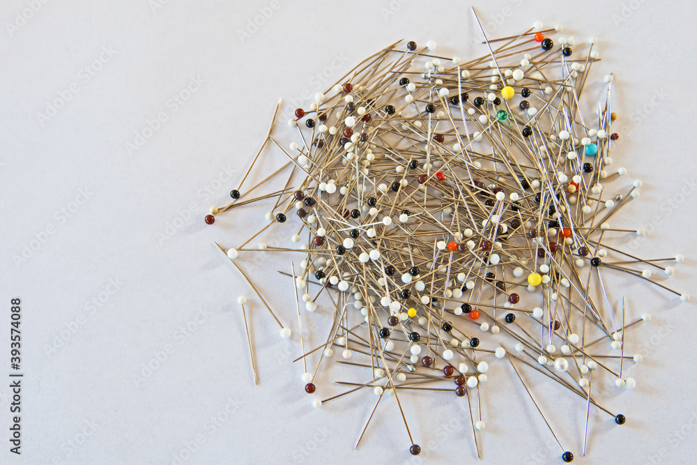 A pile of colorful glass head pins used for sewing, needlework and other projects and isolated on a white background. A pile of colorful glass head pins used for sewing, needlework and other projects and isolated on a white background.