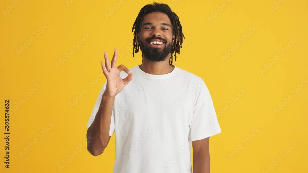 Young handsome positive african man showing okay isolated over yellow background