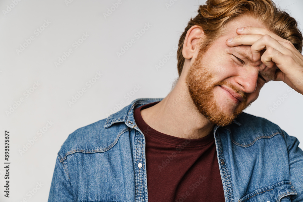Unhappy redhead guy with headache rubbing his forehead Unhappy redhead guy with headache rubbing his forehead