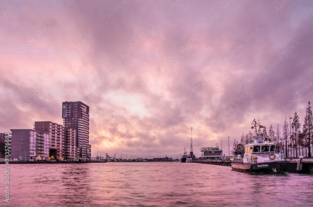 Naklejka premium Rotterdam, The Netherlands, November 17, 2020: spectacular sky at sunset over Schiehaven harbour, surrounded by industry and residential neighbourhoods