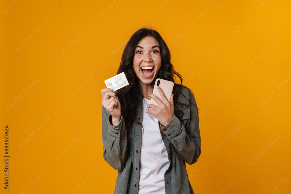 Delighted beautiful nice girl holding credit card and mobile phone Delighted beautiful nice girl holding credit card and mobile phone