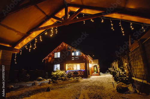 Beautiful Christmas decorations outside the house at night. House decorated with glowing lights for Christmas. Soft focus