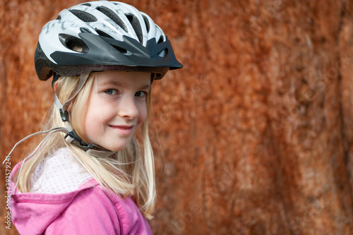 A young blonde girl poses in a cycle helmet