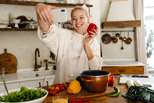 Woman taking selfie with bell pepper on cellphone while making lunch