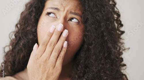 A close-up view of a bored african american woman is yawning while looking to the camera standing isolated over beige background photo