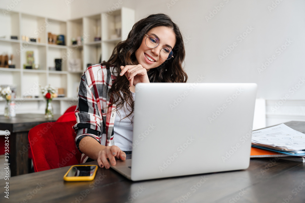 Happy nice woman working with laptop and cellphone while sitting in cafe Happy nice woman working with laptop and cellphone while sitting in cafe