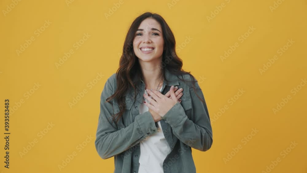 A beautiful woman is showing heart sign standing isolated over yellow background A beautiful woman is showing heart sign standing isolated over yellow background