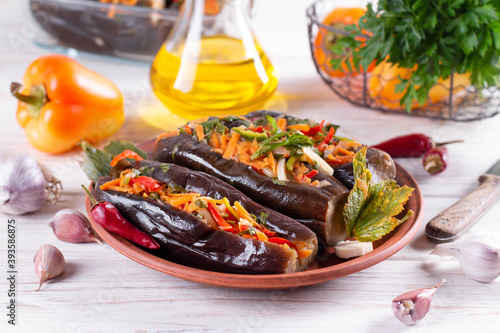 Pickled stuffed eggplant with vegetables in a plate on a wooden table