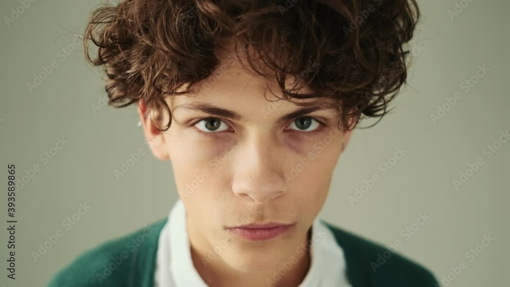 A close-up view of a surprised young man is raising his finger while come-up with an idea standing isolated over a grey wall in studio A close-up view of a surprised young man is raising his finger while come-up with an idea standing isolated over a grey wall in studio