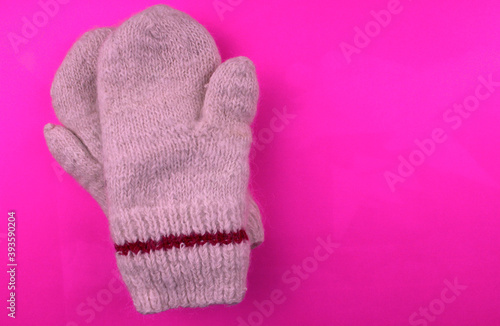 Knitted warm mittens on a pink background