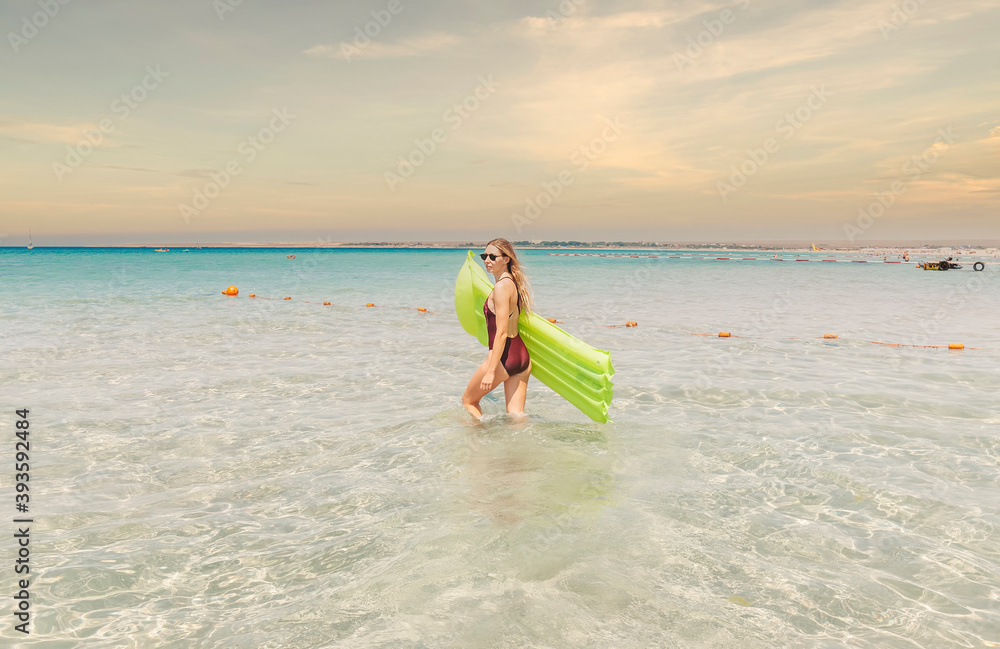 young woman in a one-piece swimsuit in the sea with an inflatable mattress