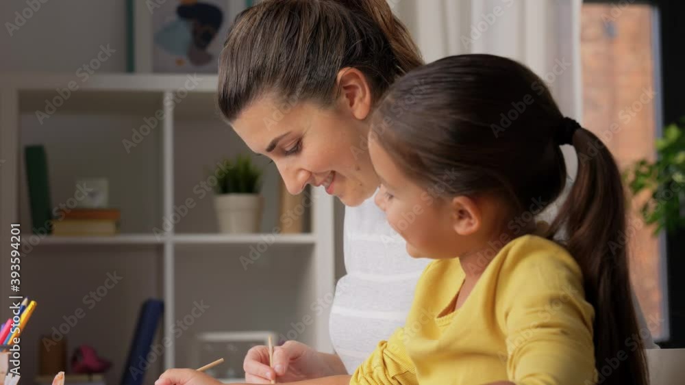 family, motherhood and leisure concept - mother spending time with her little daughter drawing with colors at home family, motherhood and leisure concept - mother spending time with her little daughter drawing with colors at home