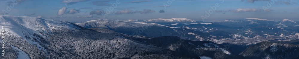 Snow and wind formed ice formations covered winter mountain plateau, tops with snow cornices in far. Magnificent sunny day on picturesque beautiful alpine ridge.