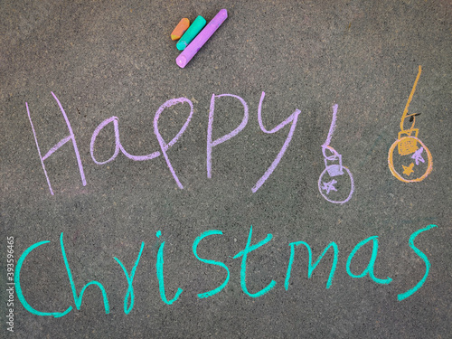 The inscription text on the grey board,Happy Christmas with jingle bells. Using color chalk pieces.