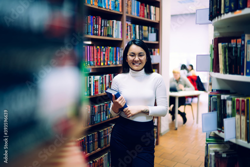 Joyful ethnic woman studying in library