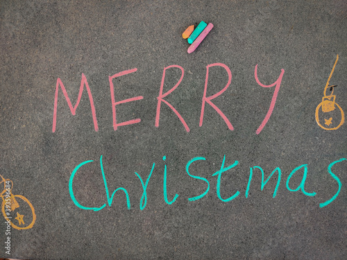 The inscription text on the grey board,Merry Christmas with jingle bells. Using color chalk pieces.