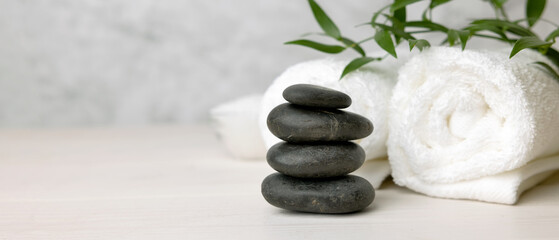 Foto auf Acrylglas Massagesalon Spa- und Wellnesscenter - Stapel Massagesteine und Handtücher mit grüner Pflanze auf weißem Holztisch. Banner kopieren Raum  © ronstik