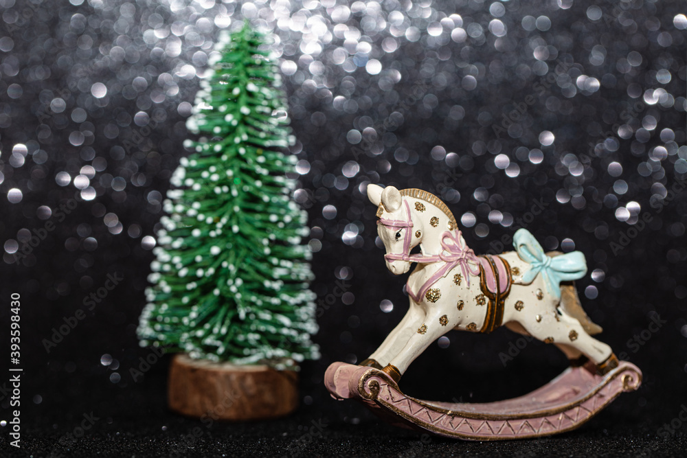 rocking horse christmas toy and christmas tree on black glitter background