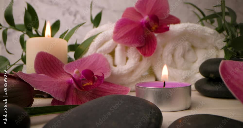 spa items - orchid flowers, massage stones with burning candles and white towel rolls. slider shot spa items - orchid flowers, massage stones with burning candles and white towel rolls. slider shot