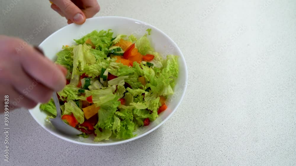 Women's hands mix salad in a large plate, cooking vegetable salad, 4K video. Vegetarian salad.