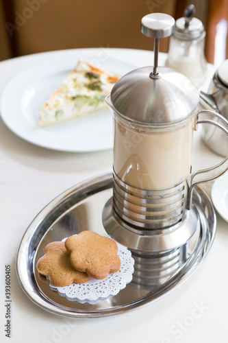 Tea with milk served in french press with cookies