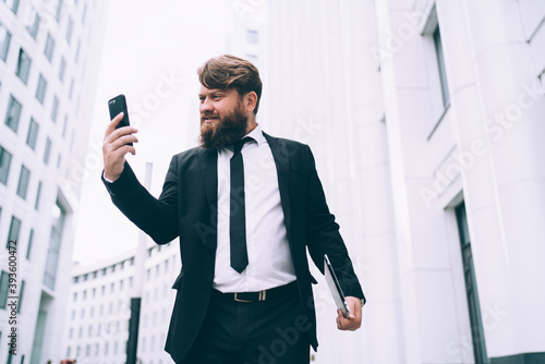 Angry businessman in formal wear using smartphone on street