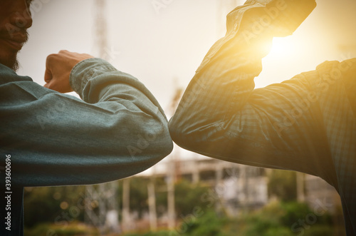 Close-up photo of two people hitting their elbows to avoid the outdoor coronavirus. Friends demonstrated a new way of greeting during healthcare concept. Spacing between people.
