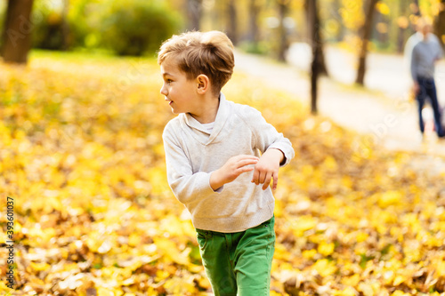 Cute little preschool child running in autumn park. Childhood, weather, catch up with you concept.
