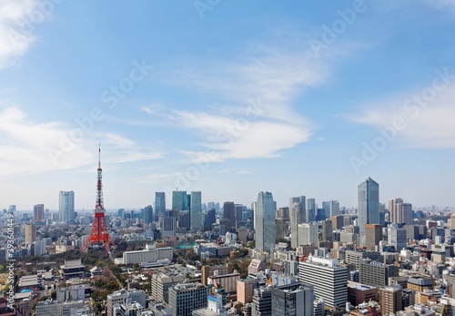 Beautiful city skyline of Downtown Tokyo, with the famous landmark Tokyo Tower standing tall among crowded skyscrapers under blue sunny sky in Tokyo, Japan. Aerial view of busy Tokyo City