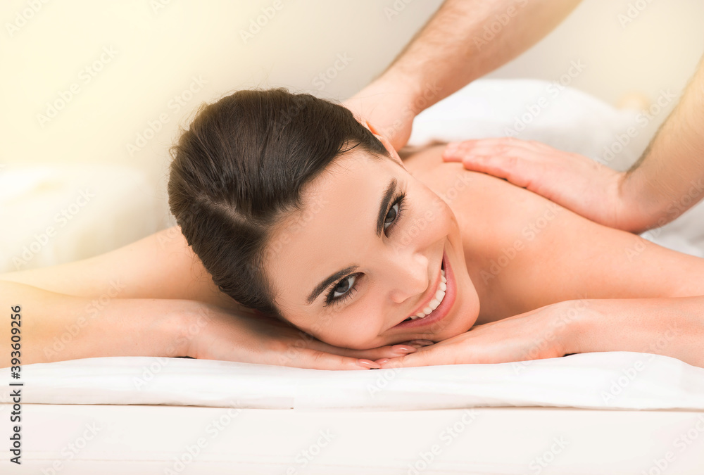 Smiling mixed race woman during a classic therapeutic back massage at a wellness spa Smiling mixed race woman during a classic therapeutic back massage at a wellness spa