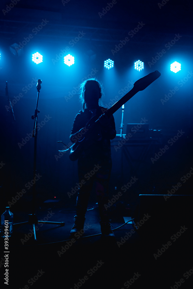 Silhouette of a girl with a guitar on the concert stage