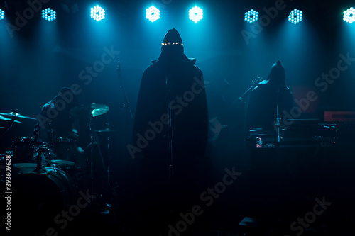 Slhouette of vocalist with hood on concert stage