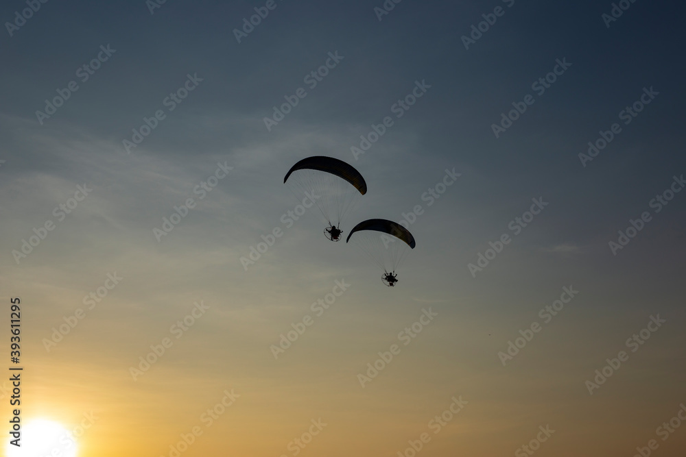 Paragliders flying with a paramotors during beautiful sunset Paragliders flying with a paramotors during beautiful sunset
