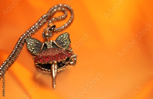 A fairy shaped shiny locket at the corner of a glowing beautiful golden or orange surface with space to write your text