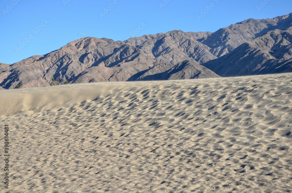 Fototapeta premium Mesquite Flat Sand Dunes in Death Valley near Stovepipe Wells in California, mountain range in the background, blue sky