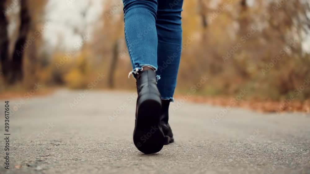 Female Feet Wearing Jeans And Shoes Walking On Road.Stylish Woman