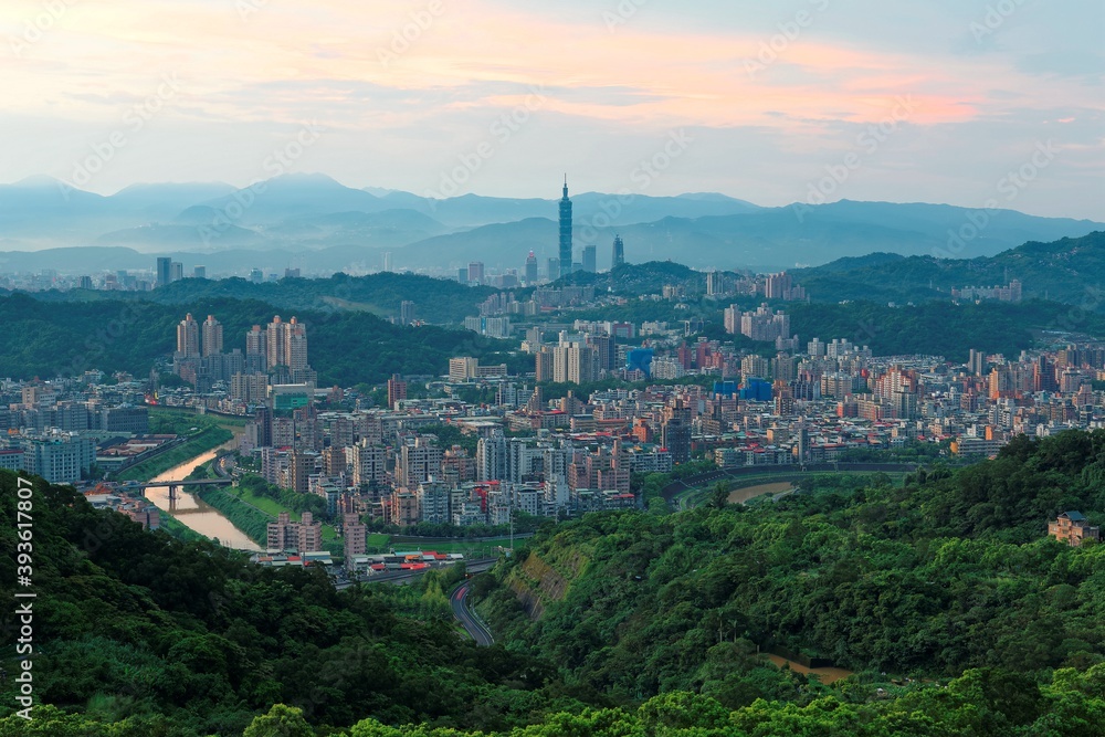 Aerial panorama of suburban residential communities in Taipei, with view of Taipei 101 Tower among skyscrapers in downtown, bridges over Xindian River & mountain silhouettes in the distant background