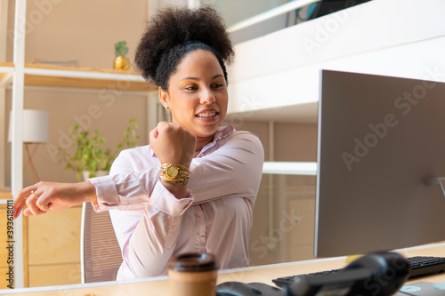Happy black business woman stretching arms in workstation. health, ergonomics, wellbeing concept.. photo