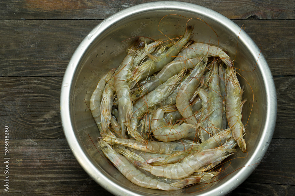 Fresh white tiger prawns in a metal cup on a wooden table. Fresh shrimp for cooking in the kitchen. Fresh white tiger prawns in a metal cup on a wooden table. Fresh shrimp for cooking in the kitchen.