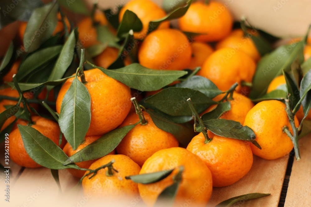 Juicy tangerines with green leaves in a wooden box 