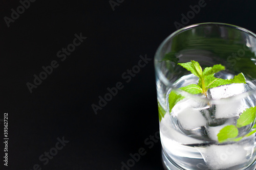 A glass with ice cubes and a sprig of mint on the right side of the screen.