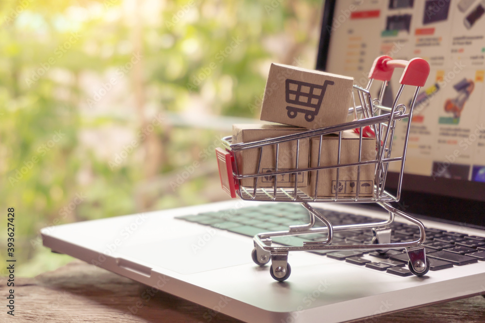 Shopping online concept - Parcel or Paper cartons with a shopping cart logo in a trolley on a laptop keyboard. Shopping service on The online web. offers home delivery..