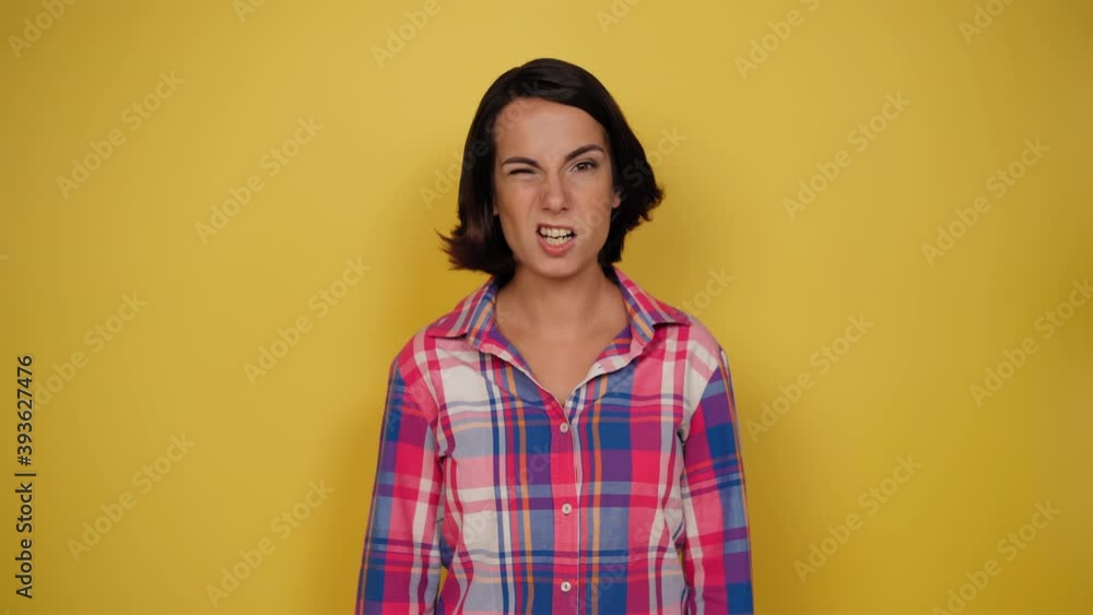 Girl expressing doubt or hesitation looking to camera. Woman in a plaid shirt on yellow background. Good for VFX. Human emotions, facial expression concept. High quality 4k resolution footage. Girl expressing doubt or hesitation looking to camera. Woman in a plaid shirt on yellow background. Good for VFX. Human emotions, facial expression concept. High quality 4k resolution footage.
