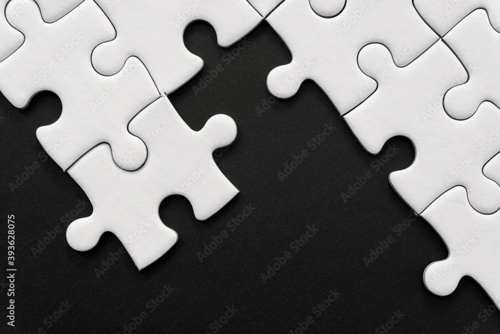 Unfinished white jigsaw puzzle pieces on black background with copy space Unfinished white jigsaw puzzle pieces on black background with copy space