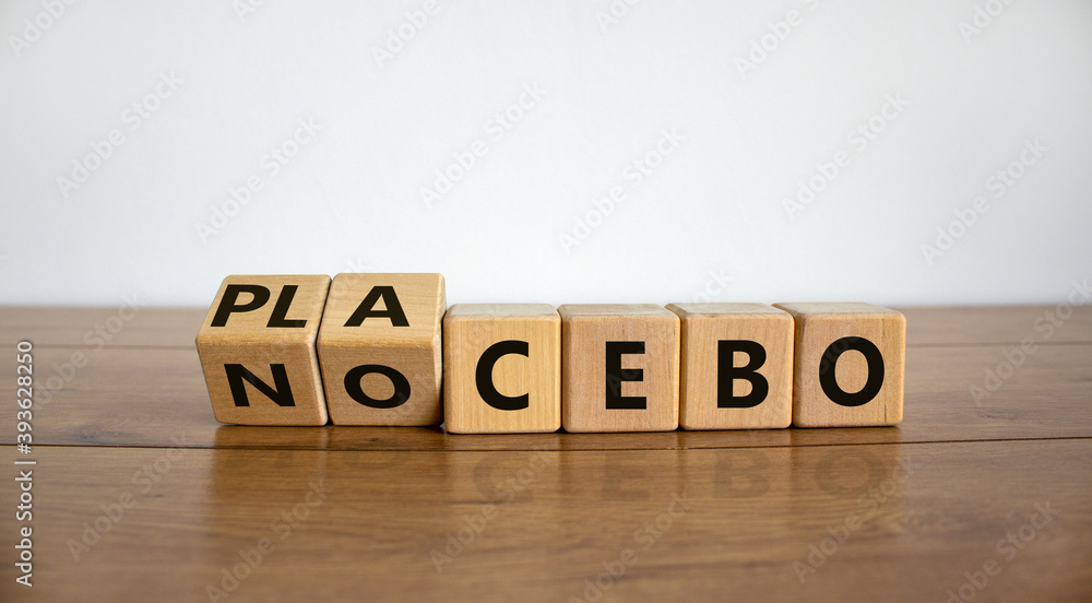 Nocebo or placebo. Turned cubes and changed the word 'placebo' to 'nocebo', or vice versa. Beautiful wooden table, white background, copy space. Medical and science concept. Nocebo or placebo. Turned cubes and changed the word 'placebo' to 'nocebo', or vice versa. Beautiful wooden table, white background, copy space. Medical and science concept.