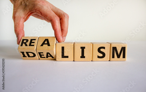 Male hand turns cubes and changes the expression 'idealism' to 'realism' or vice versa. Beautiful white background. Business concept. Copy space. photo