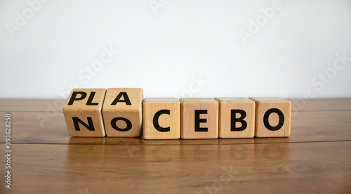 Nocebo or placebo. Turned cubes and changed the word 'placebo' to 'nocebo', or vice versa. Beautiful wooden table, white background, copy space. Medical and science concept. photo