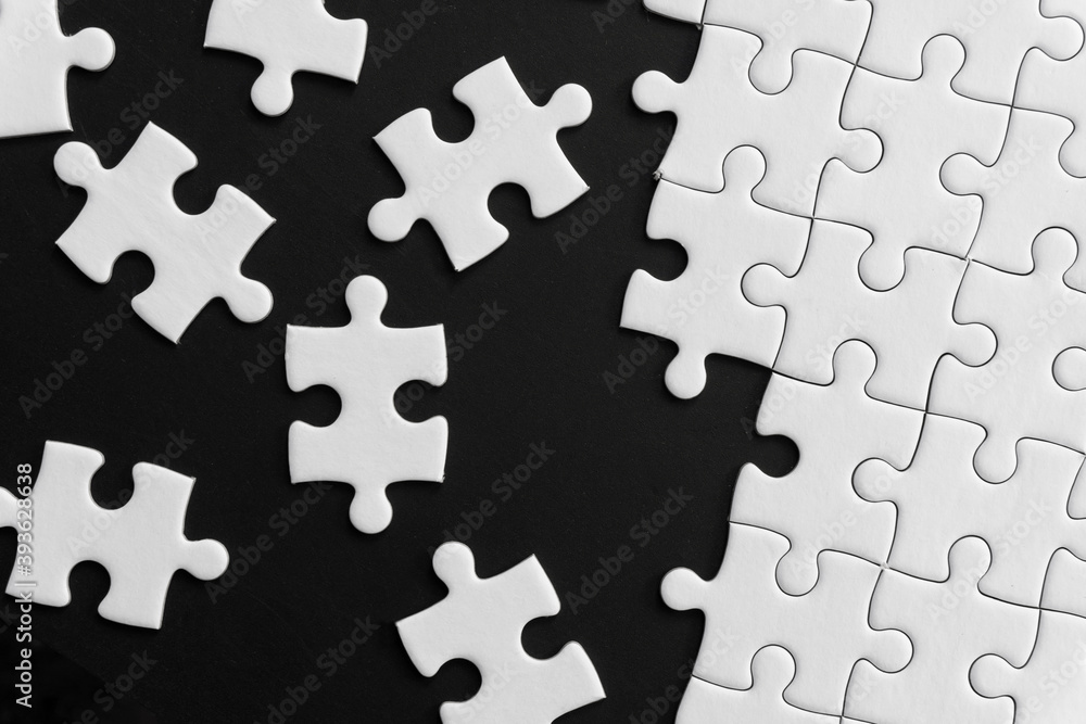Unfinished white jigsaw puzzle pieces on black background Unfinished white jigsaw puzzle pieces on black background